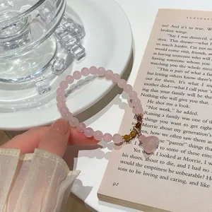 Detailed close-up view of natural pink crystal bracelet with cute peach pendant detail.