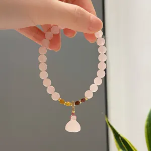 Close-up detail of the pink crystal beaded bracelet featuring a delicate gourd pendant.