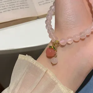 Exquisite rose quartz peach bracelet detail featuring sweet pink crystal beads and cute charm.