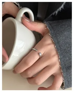 Minimalistischer silberner Tropfen-Offenring im Detail, elegante geometrische Finger-Schmuck.