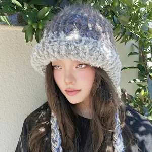 Detailansicht der bunten Plüsch-Strickmütze mit Ohrenklappen und modischen Zöpfen für den Winter.