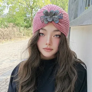Pink knitted turban beanie with rhinestone flower detail, perfect for cozy winter wear style.