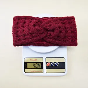 Detailed view of the red knit headband showing crochet texture and weight on scale.