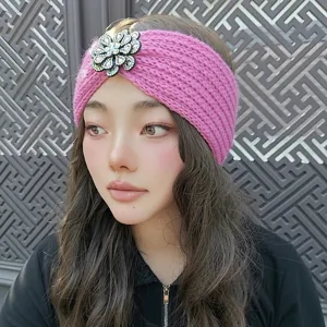 Close-up view of a pink knitted headband featuring a sparkling rhinestone flower detail.