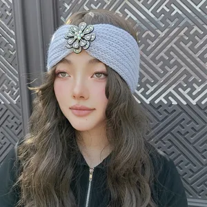 Close-up detail of grey knitted headband featuring sparkling rhinestone flower ornament.