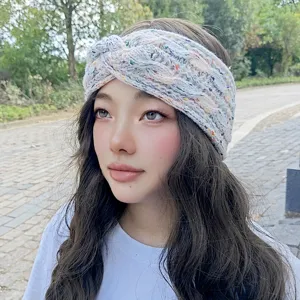 Cozy knitted winter headband with colorful speckles, thick fleece-lined crossover design for warmth.