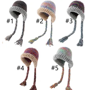 Detailansicht der bunten Strickmütze mit Ohrenklappen, Plüschrand und langen geflochtenen Quasten.