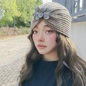 Close-up view of the grey knitted turban hat featuring sparkling rhinestone flower decor.