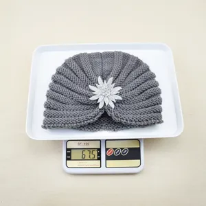 Detail view of the grey knitted turban hat featuring a sparkling crystal flower brooch.