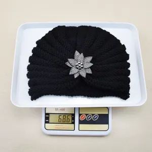 Black knitted turban hat featuring a sparkling rhinestone flower brooch for warm autumn winter.
