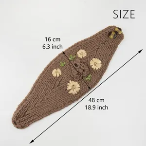 Dettaglio della fascia per capelli floreale in maglia marrone con ricamo e chiusura a bottone.