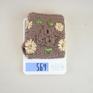Vista dettagliata della fascia in maglia marrone con fiori di camelia in nastro, morbido accessorio.