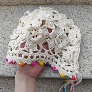 Handmade crochet hollow bonnet hat detail, beige knit cap with colorful wooden beads and tassels.