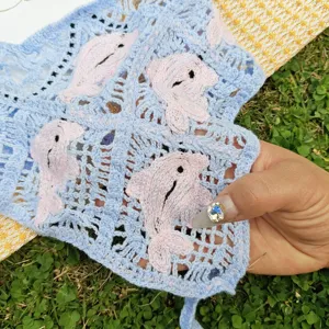Primo piano dettagliato del foulard triangolare in maglia traforata, graziosa fascia.