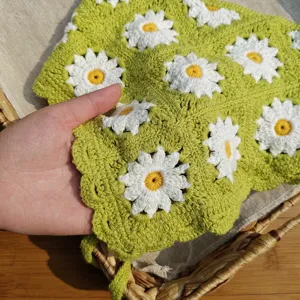 Close-up of green knitted daisy hairband, handmade crochet floral pattern with cute ties.