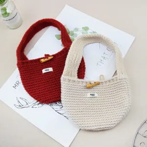 Dettaglio borsa a mano in maglia con lana morbida, bottone in corno e simpatica etichetta.