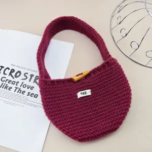 Vista dettagliata della borsa a mano in lana lavorata a maglia con bottone e etichetta.