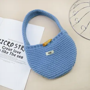 Vista dettagliata ravvicinata di un'elegante borsa a mano in maglia blu con bottone in legno.