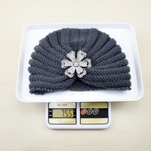 Detail shot of dark grey knit turban hat with dazzling rhinestone flower brooch, warm winter fashion.