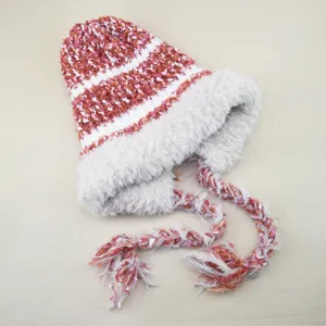 Detailed view of the plush knit beanie with fluffy lining, braided tassels and warm ear flaps.