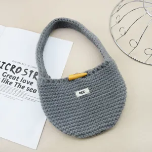 Primo piano dettagliato della bellissima borsa in morbida lana grigia con bottone.