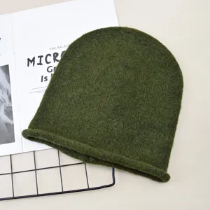Detailed view of the dark green knit beanie showing soft wool texture and rolled cuff design.
