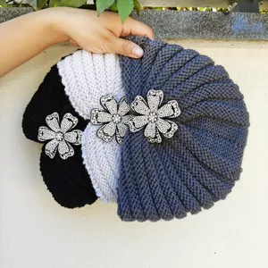 Detailed view of handmade knitted turban hats featuring sparkling crystal flower brooches for winter.