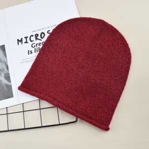 Red knitted beanie hat, simple solid color roll-edge design, cozy warm winter headwear.