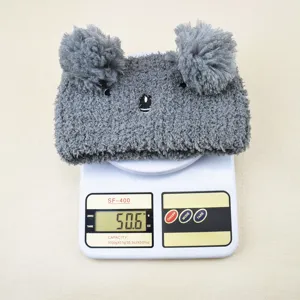 Grey coral fleece animal headband detail, cute pom pom ears design, soft fabric texture close up.