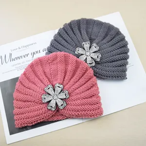 Detailed view of winter warm knitted turban hat with sparkling rhinestone flower brooch accessory.