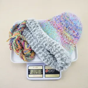 Detailaufnahme des bunten Strick-Slouch-Mützen- und Plüschschal-Sets auf einer Waage.