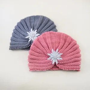 Detailed view of winter warm knitted turban hats with sparkling rhinestone flower brooch accents.