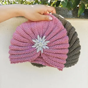 Close-up detail of the stylish knitted turban hat featuring a sparkling rhinestone flower brooch.