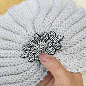 Gros plan de la broche fleur en strass sur bonnet turban en tricot gris pour l'hiver.