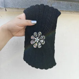 Close-up of black knitted headband with sparkling rhinestone flower brooch detail.