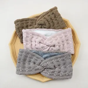 Detail shot of cozy knitted headband with cross twist design and soft plush inner lining.