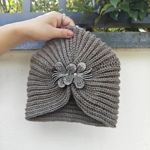 Close-up of the brown knitted turban hat showcasing the sparkling rhinestone flower brooch detail.