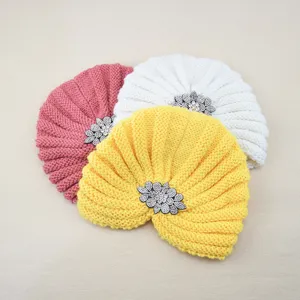 Vue détaillée du bonnet en tricot orné d'une fleur en strass, accessoire chaud d'hiver.