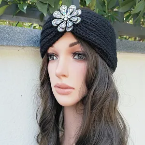 Close up of black knitted headband detail featuring sparkling crystal rhinestone flower decoration.