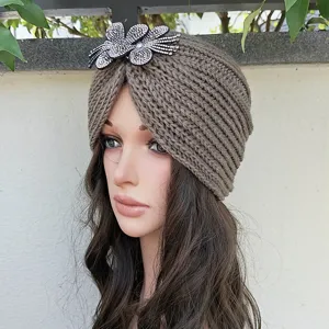 Detail view of brown knitted turban hat featuring sparkling rhinestone flower decoration.
