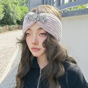 Detailed view of a cozy knitted headband featuring sparkling rhinestone flower decor for cold days.