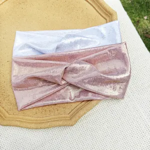Detailansicht glänzender metallischer Twist-Haarbänder in Silber und Rosa, weicher Stoff.