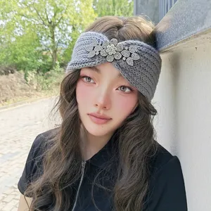 Close-up detail of grey knitted headband with sparkling rhinestone floral charm for women.