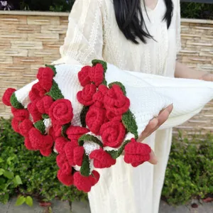 Dettaglio coperta di rose all'uncinetto fatta a mano che mostra fiori rossi su tessuto a maglia bianca.
