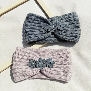 Detailed view of stylish knitted winter headbands featuring sparkling rhinestone floral decorations.