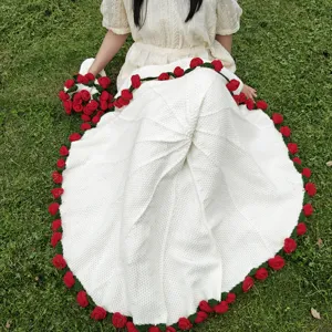 Coperta lavorata a uncino con rose rosse fatte a mano e foglie verdi per decorazione accogliente.