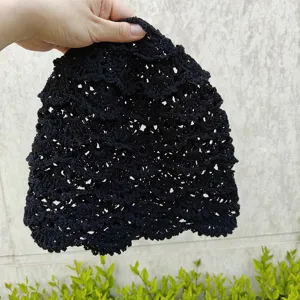 Gros plan détail du bonnet slouchy noir fait main en crochet ajouré texture tricot.