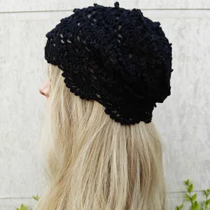Vue détaillée d'un bonnet slouchy en tricot noir ajouré, montrant texture et style.
