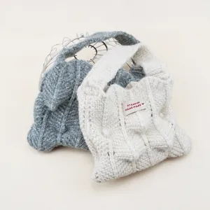 Primer plano de bolso de mano de lana tejida con diseño plisado, accesorio de invierno.