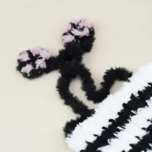 Detailed shot of cute fluffy black and white striped warm hat with playful paw plush design.